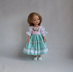 a doll wearing a dress and shoes standing in front of a white wall with a gray background