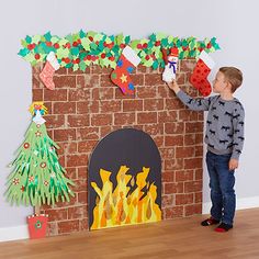 a young boy standing in front of a fireplace decorated with paper christmas stockings and stockings