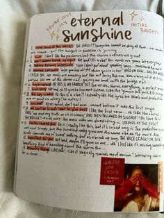 an open notebook with writing and pictures on the inside pages, in which someone is holding their hand