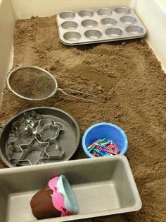 a sandbox with cupcakes, muffin tins and baking utensils in it