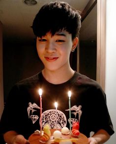 a young man holding a cake with candles on it