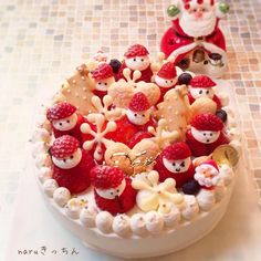 a white cake topped with lots of fruit and santa clause figurines on top of it