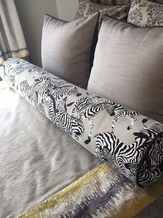 a zebra print pillow on top of a bed next to two pillows and a blanket