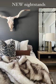 a bed room with a neatly made bed and a cow skull mounted on the wall