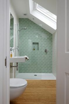 a small bathroom with a skylight above the toilet and bathtub, along with a wooden floor