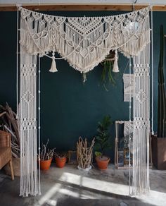 a room with green walls and white macrame hanging from it's ceiling