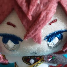 a close up of a stuffed animal with pink hair and blue eyes