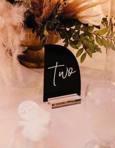 there is a place card holder with the word tue on it next to some flowers