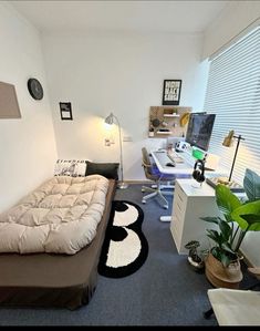 a small bedroom with a bed, desk and computer monitor on the wall in it