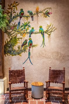 two chairs sitting in front of a wall with birds on it's back legs