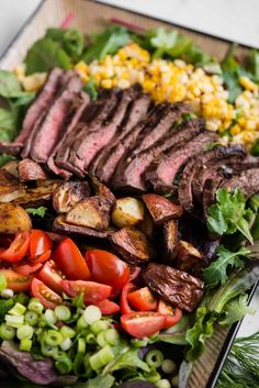 steak and vegetables with corn on the cob in the backgroung are ready to be eaten