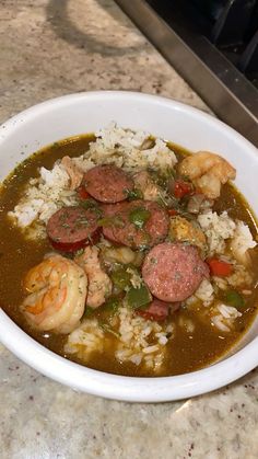 a white bowl filled with meat and rice on top of a counter next to a stove