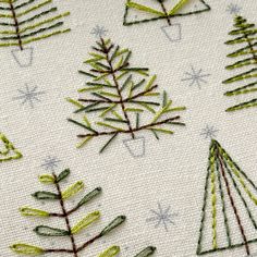 embroidered christmas trees on white fabric with snowflakes and stars in the back ground