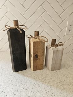 three wooden bottles tied with twine on top of a white countertop next to a light switch