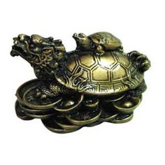 an ornate brass turtle on top of a tortoise shell with two smaller turtles sitting on it's back