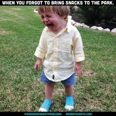 a little boy that is standing in the grass with his mouth open and tongue out