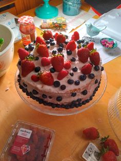 a cake with strawberries and blueberries on it sitting on a table next to other desserts