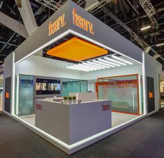 an exhibit booth at a trade show with orange and white lighting on the front wall