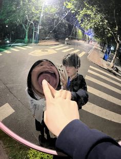 a person taking a selfie in front of a mirror with another person pointing at it