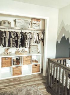 a baby's room with mountains painted on the wall and an open crib