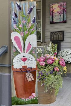 a painting of a bunny in a flower pot on the side of a house door