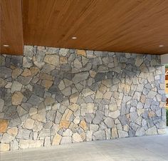 a large stone wall next to a wooden ceiling