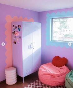 a room painted in pink and purple with a heart shaped bean bag on the floor