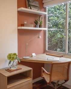 a desk with a chair, lamp and bookshelf in front of a window