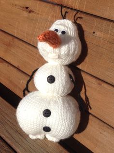 two knitted snowmen sitting next to each other on top of a wooden bench