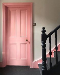 a pink door is next to a black banister