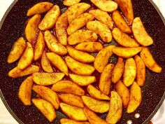 some fried potatoes are being cooked in a frying pan with brown sauce on the side