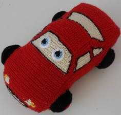 a crocheted red car with eyes and nose