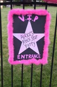 a pink and black sign that is on top of a gate in front of some grass