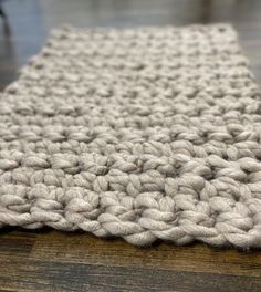 a close up view of a crocheted rug on a wooden floor with a person in the background