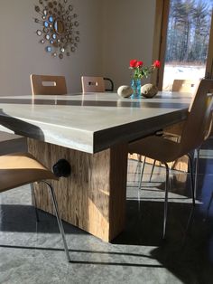 a dining room table with chairs around it and a vase on the table next to it