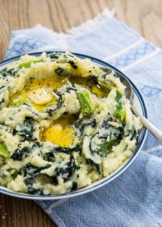 a bowl filled with mashed potatoes and spinach on top of a blue napkin