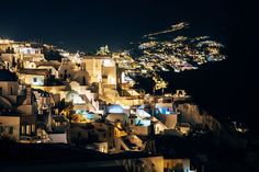 a night time view of a city with lights and buildings on the top of it