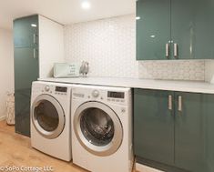 a washer and dryer in a room with green cabinetry on the walls