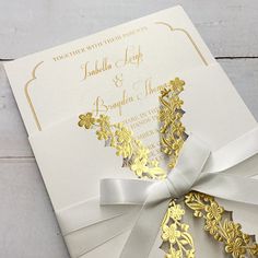 a white and gold wedding card with a bow