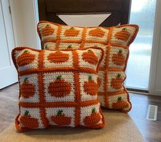 two crocheted pumpkin pillows sitting on top of a wooden floor next to a door