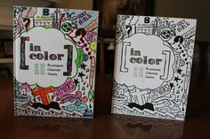 two coloring books sitting on top of a wooden table