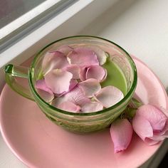 pink flowers are in a glass jar on a pink plate