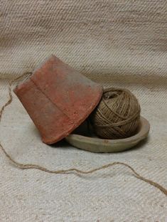 two balls of yarn in a wooden bowl and an old hammer on the ground next to it