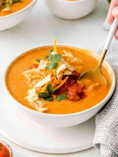 a person holding a spoon in a bowl of soup