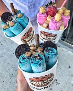 three ice cream cones with cookies and strawberries in them are being held by someone's hand