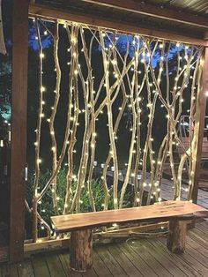 a wooden bench sitting next to a window covered in fairy lights and tree branches on a deck