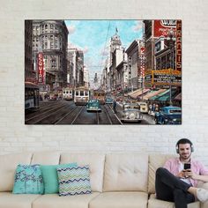 a man sitting on a couch looking at his cell phone in front of a cityscape