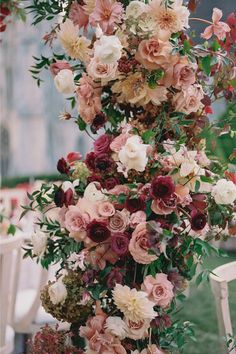 a bunch of flowers that are on top of a table in front of some chairs