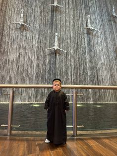 a young boy standing in front of a waterfall