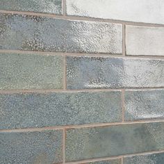 a close up of a brick wall with gray and white tiles on the bottom half